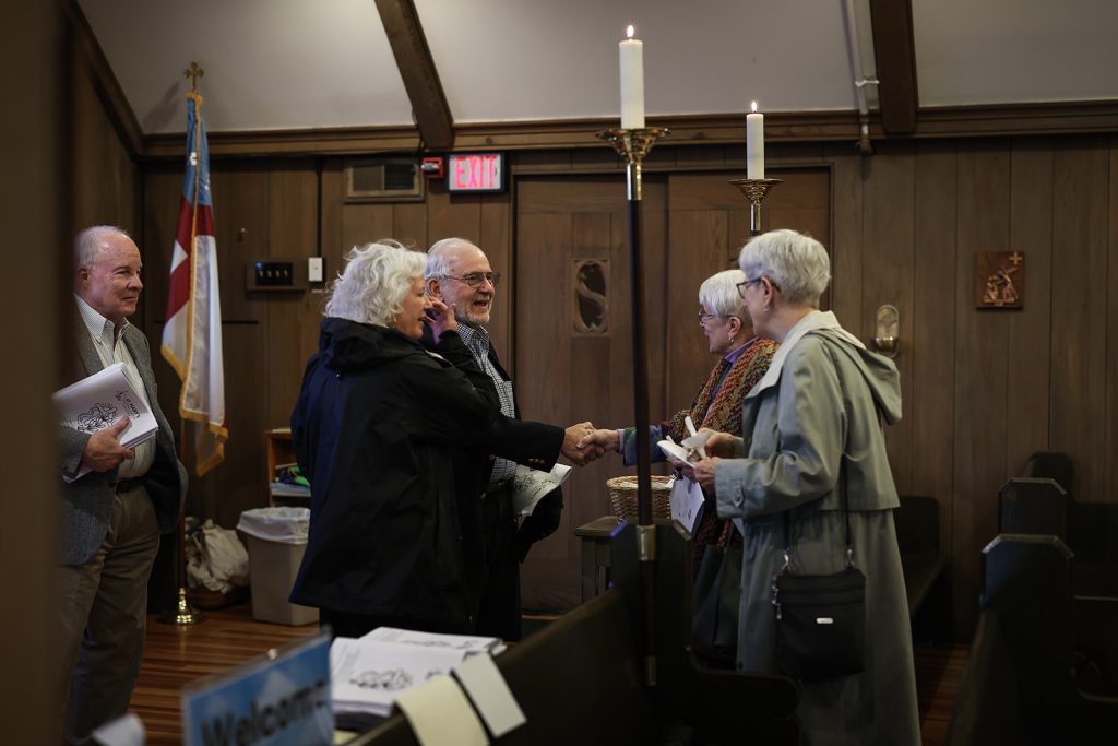 an elderly man and woman smiling and being greeted by two women who are wearing raincoats