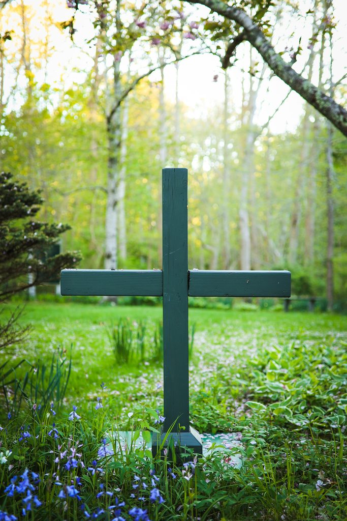 a grave site with a cross surrounding by purple flowers