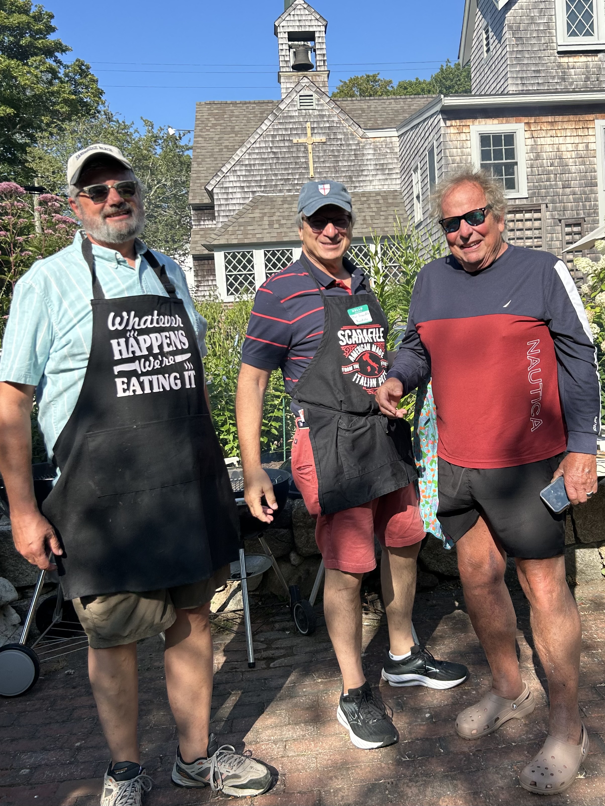 Three men in aprons pose at the St. Mary's Summer Cookout